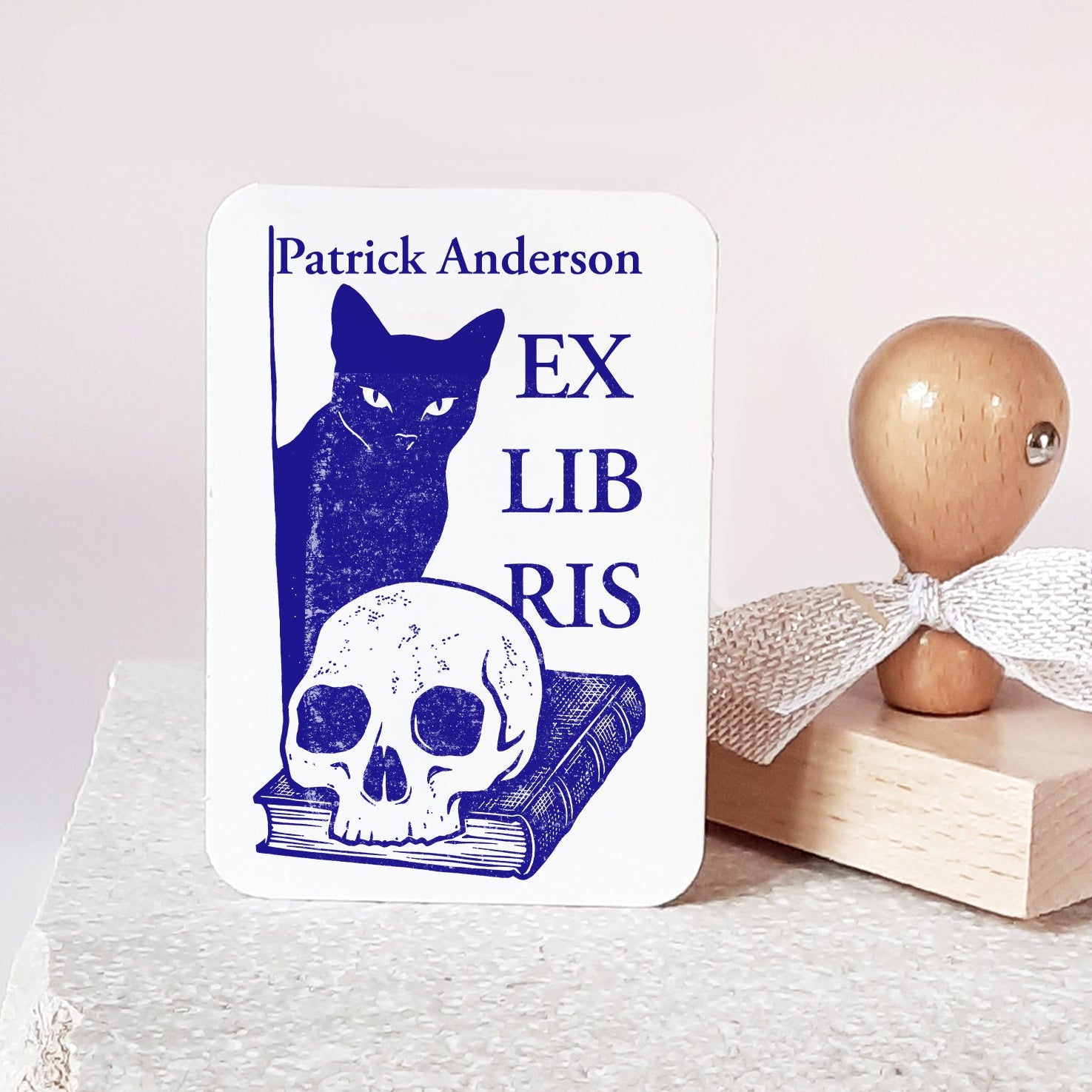 Custom book stamp with a Memento Mori design featuring a black cat, a skull, and a book. This is an high-quality, personalized wood rubber stamp, with  handmade wooden handle wrapped with a decorative ribbon, highlighting a unique, luxury gift for book collectors, avid readers, and personal library enthusiasts.
custom book stamp
Memento Mori design
personalized wood rubber stamp
Ex Libris
book collectors
luxury gift for book lovers
