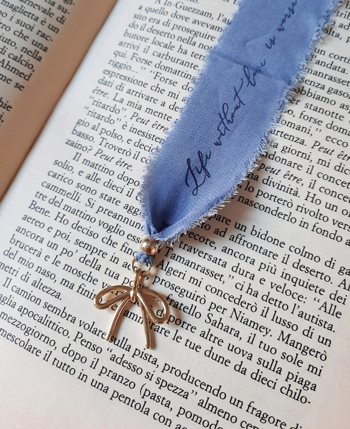 Handmade personalized silk bookmark resting between the pages of an open book